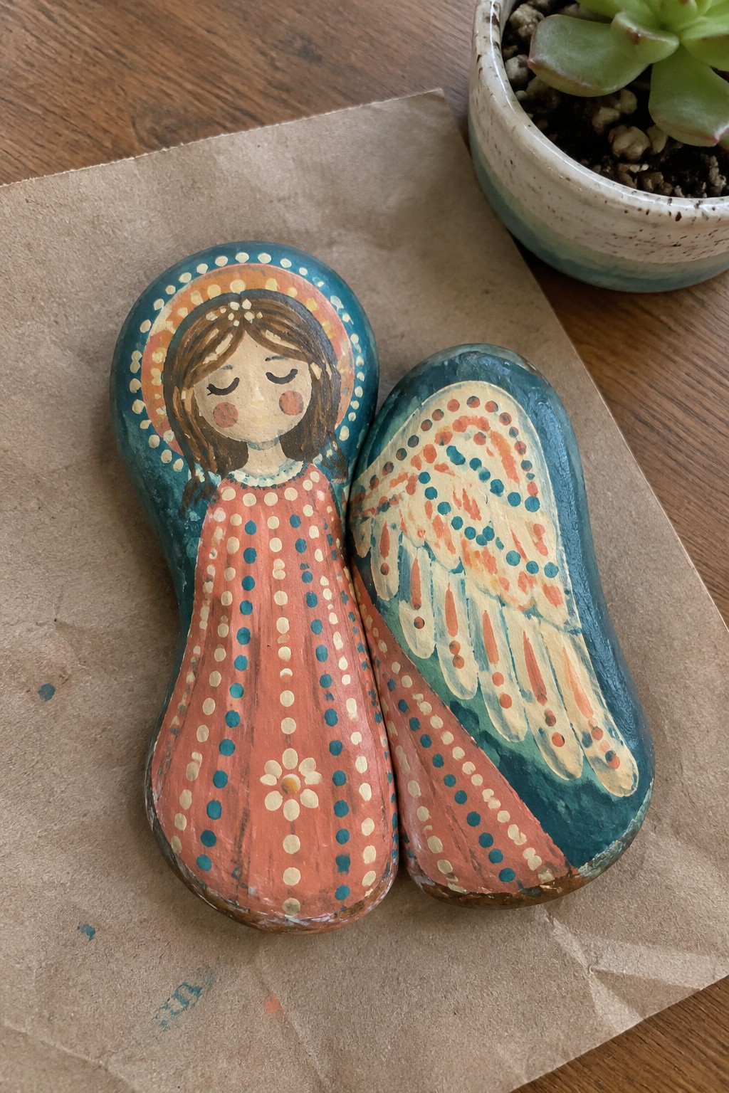 Painted angel rocks with halo, polka-dot dress, flower, and dotted wings on paper