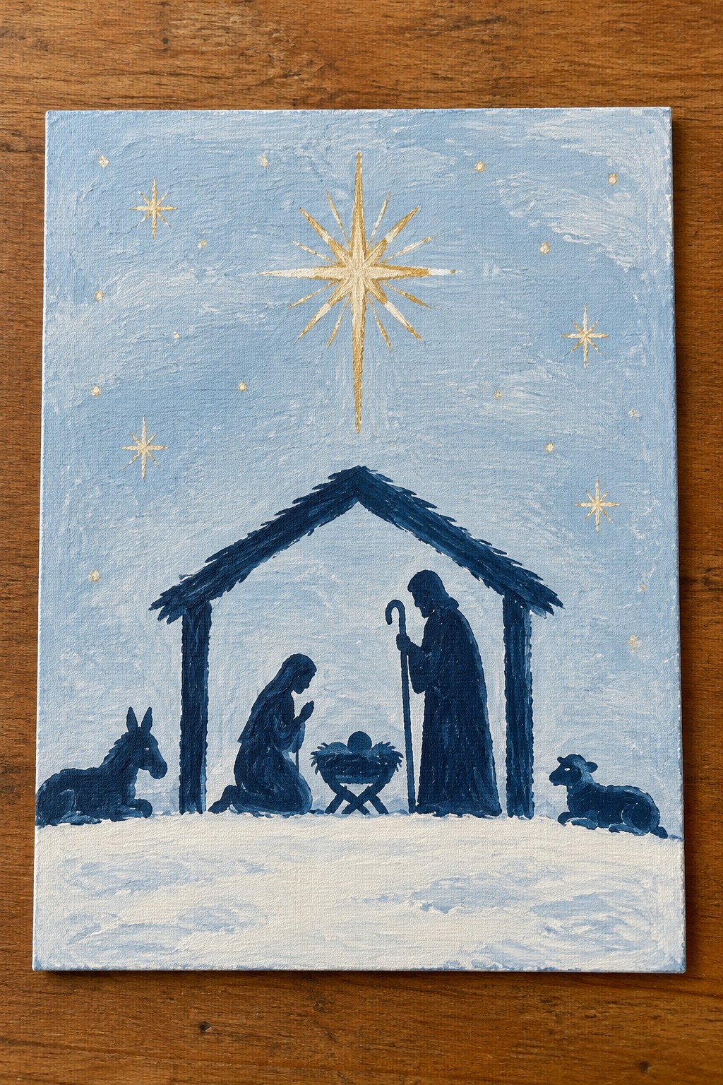 Nativity painting with Mary kneeling, Joseph holding staff, baby in manger, donkey, sheep and golden star.