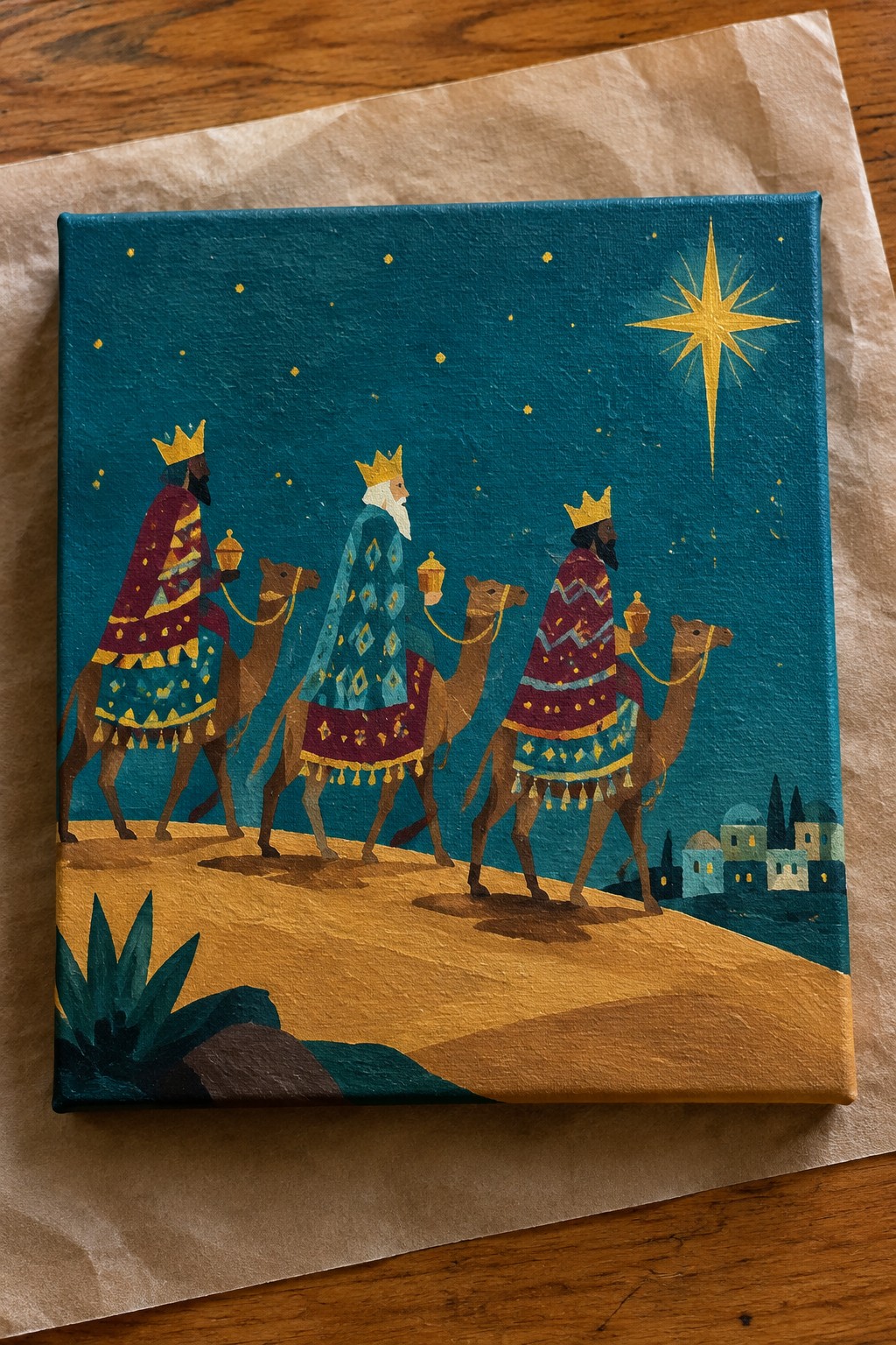Three crowned kings in patterned robes ride camels under a glowing star toward a village.