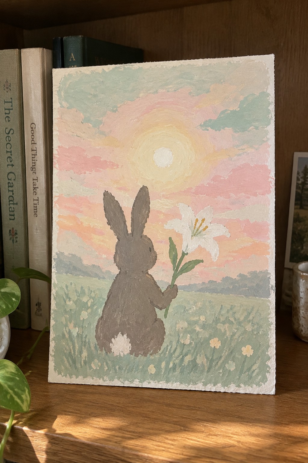 Brown rabbit holding white lily in flower field under pastel sunset sky.