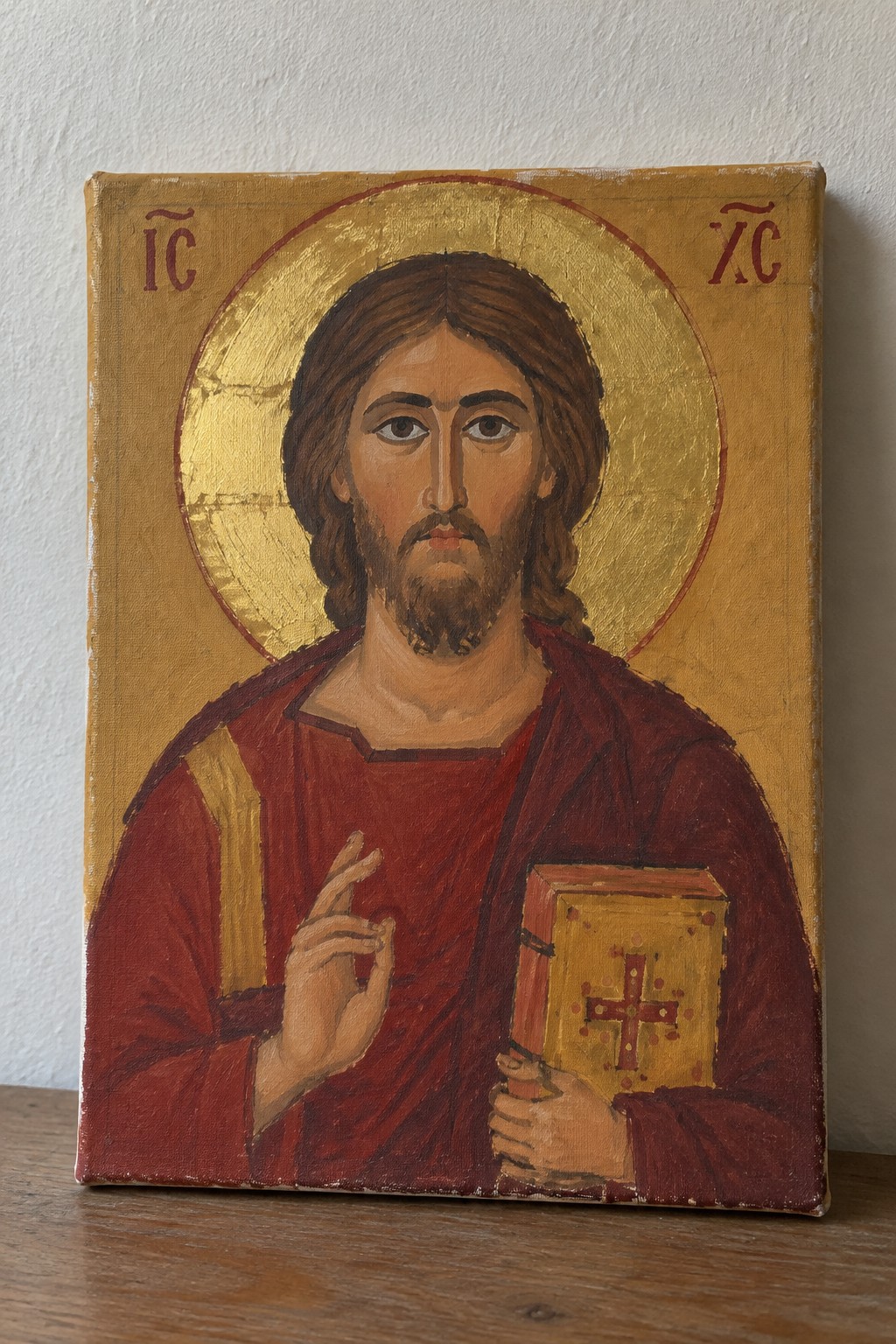 Byzantine icon of Christ in red robe holding gold book with halo