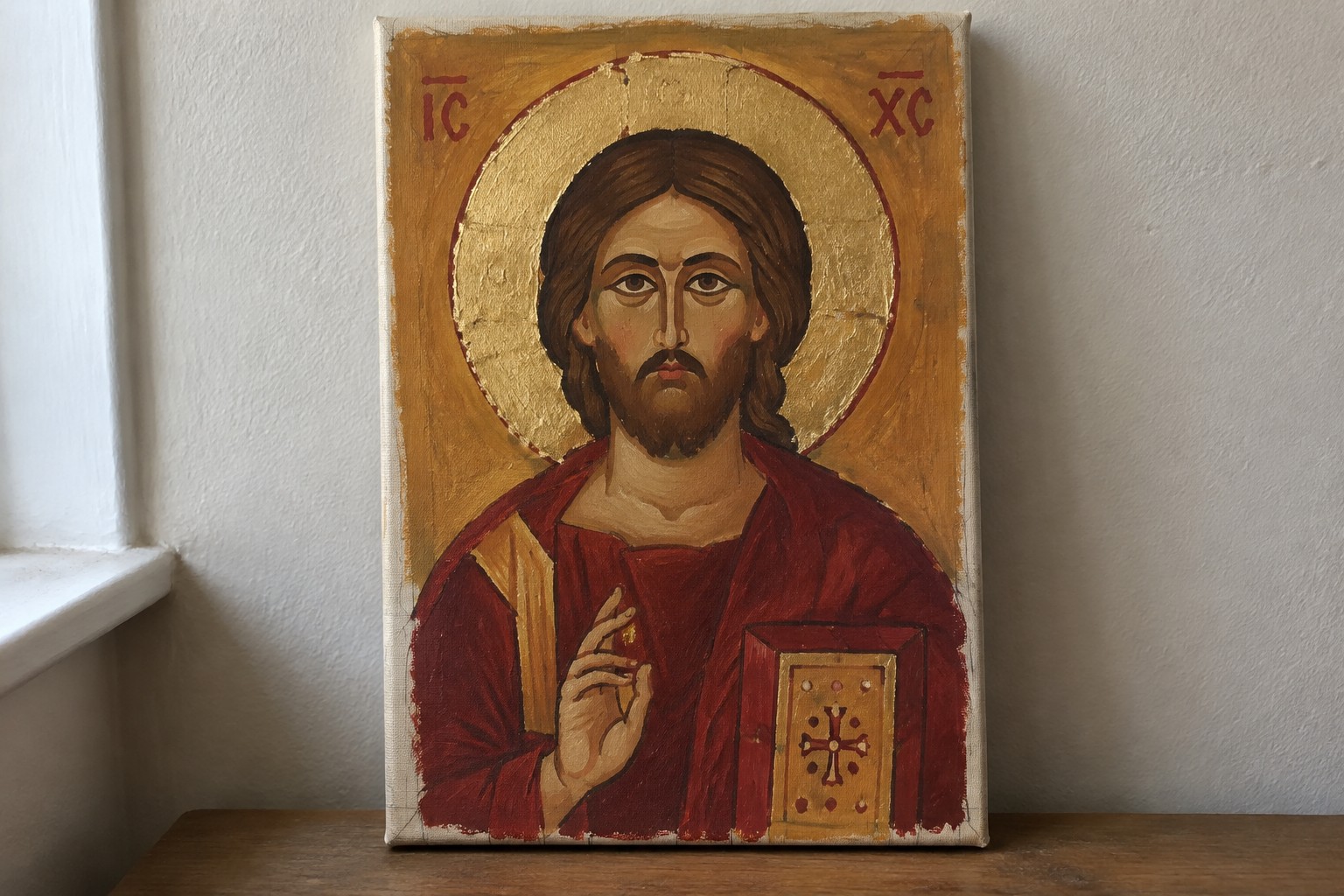 Byzantine icon of Christ in red robe holding gold book with halo