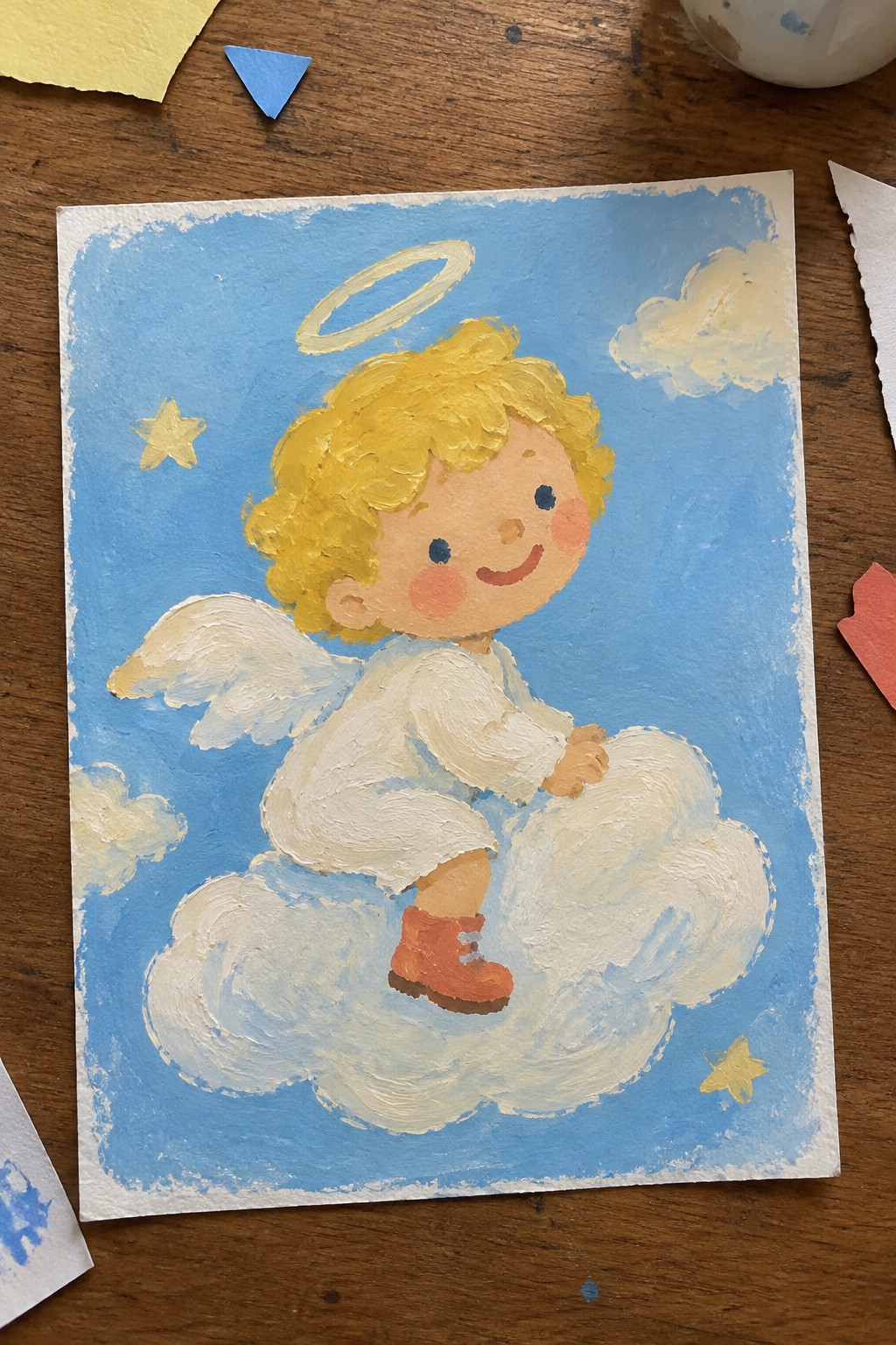 Blonde angel child with halo and wings sitting on cloud in blue sky with stars