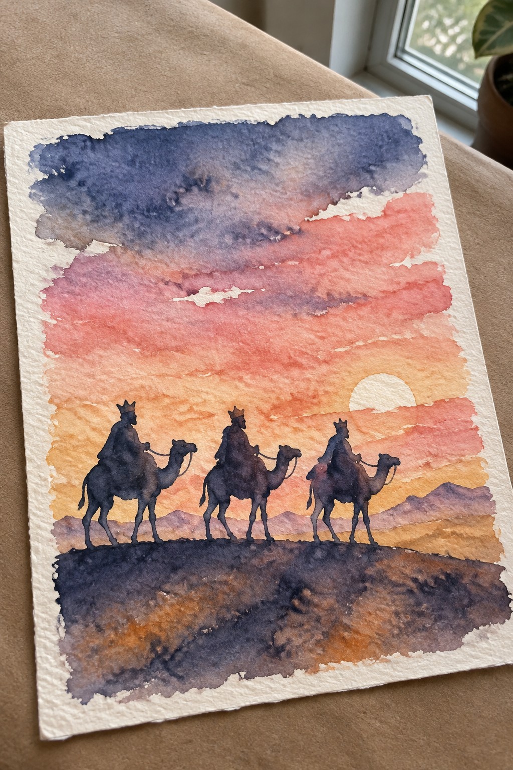 Three crowned figures on camels silhouetted against a vibrant desert sunset in watercolor