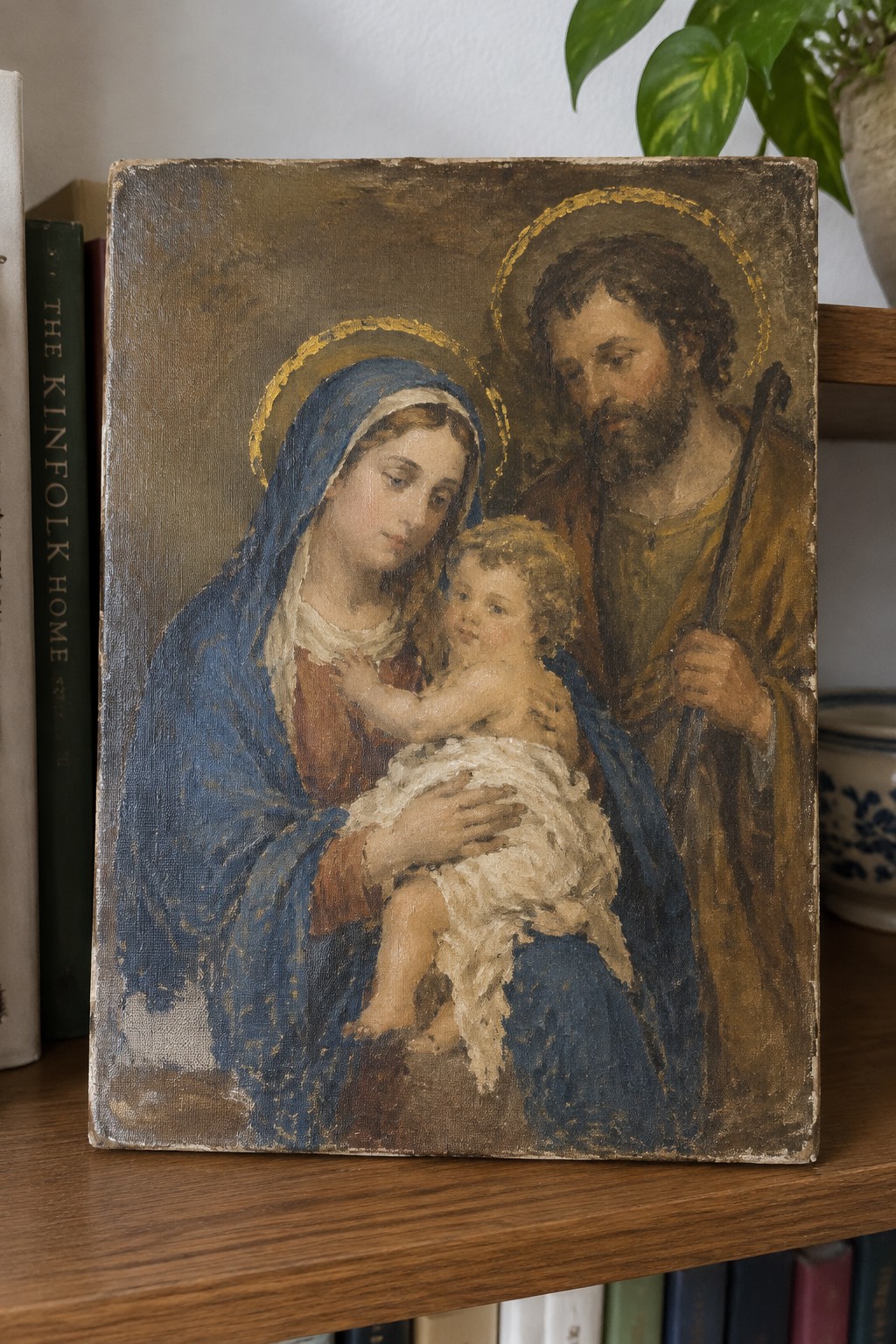 Old painting of haloed Mary in blue holding baby Jesus beside staff-holding Joseph.