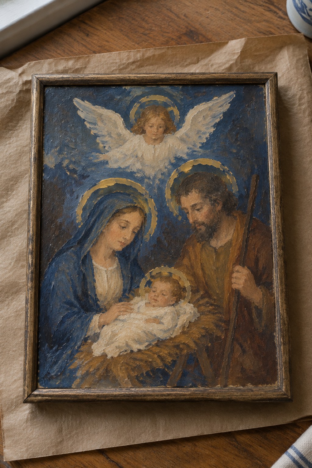 Framed oil painting of Mary in blue veil, Joseph with staff, haloed infant and angel.