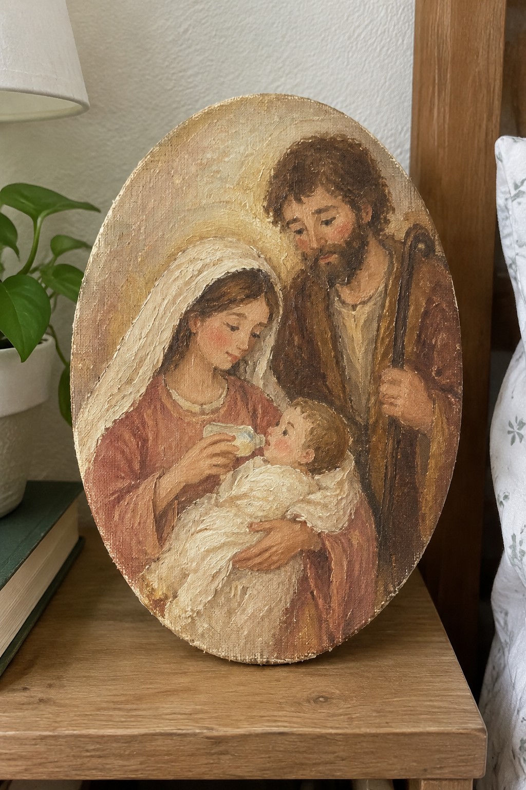 Oval painting of woman in red robe bottle-feeding baby beside bearded man with staff