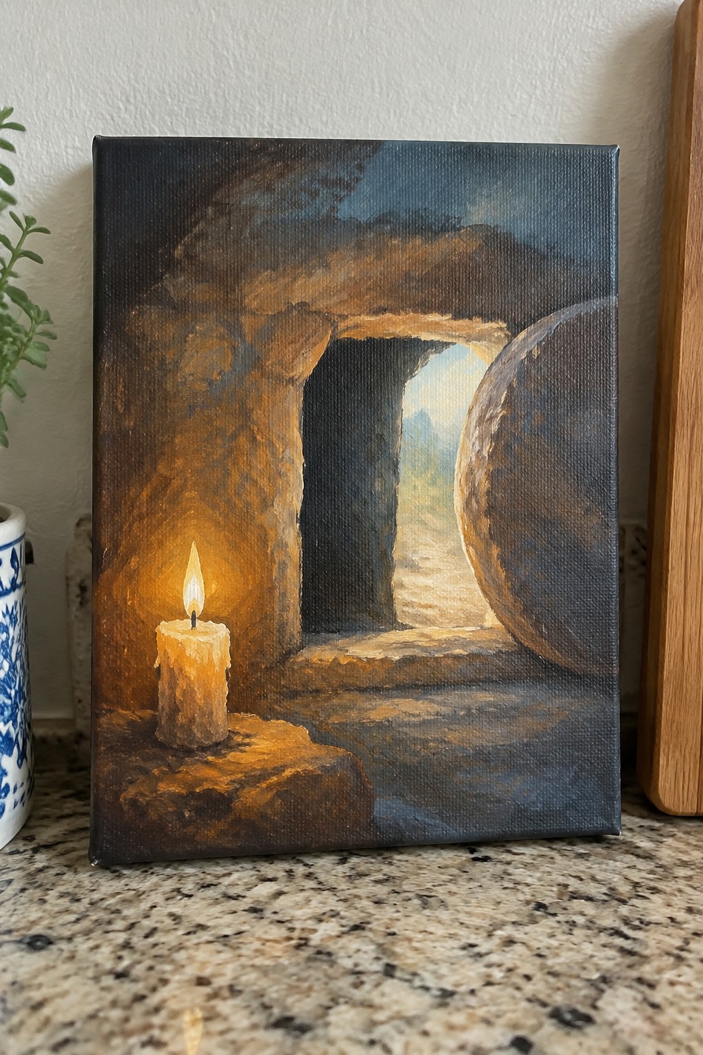 Lit candle glows in dark rocky tomb beside large rolled stone at entrance