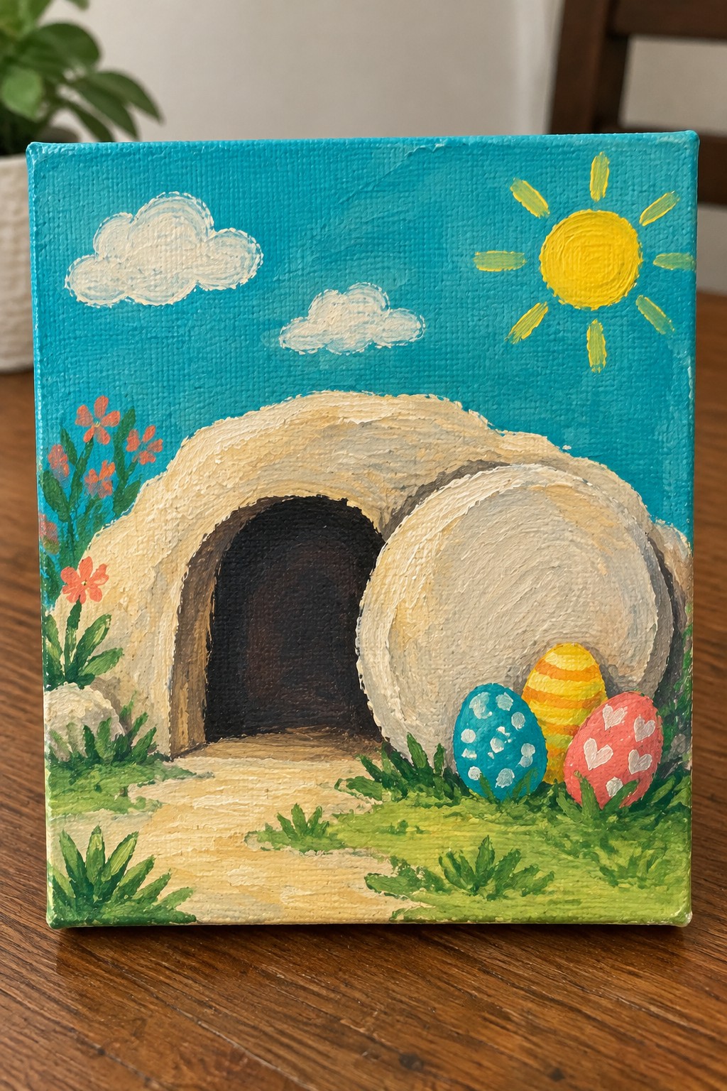 Vibrant painting of empty cave tomb with blue, yellow, and pink Easter eggs in sunlight