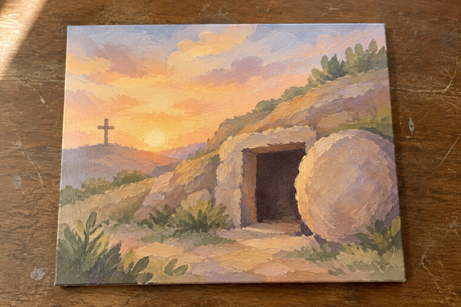 Sunrise painting of empty tomb with large stone rolled aside and hilltop cross