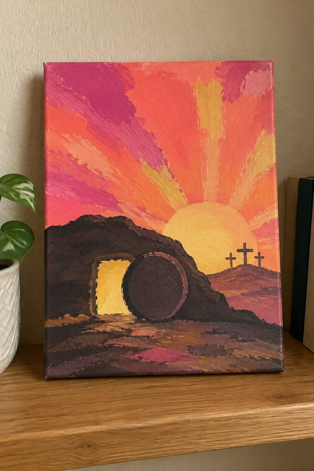 Vibrant painting of open tomb with rolled stone and three crosses under colorful sunrise
