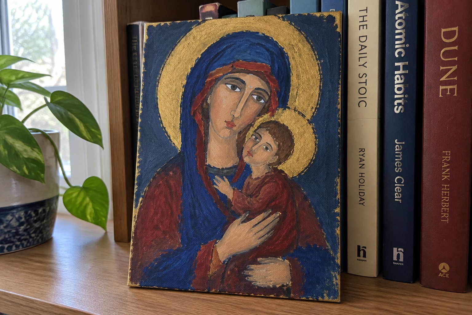 Madonna and Child icon in blue and red robes with gold halos on wooden shelf