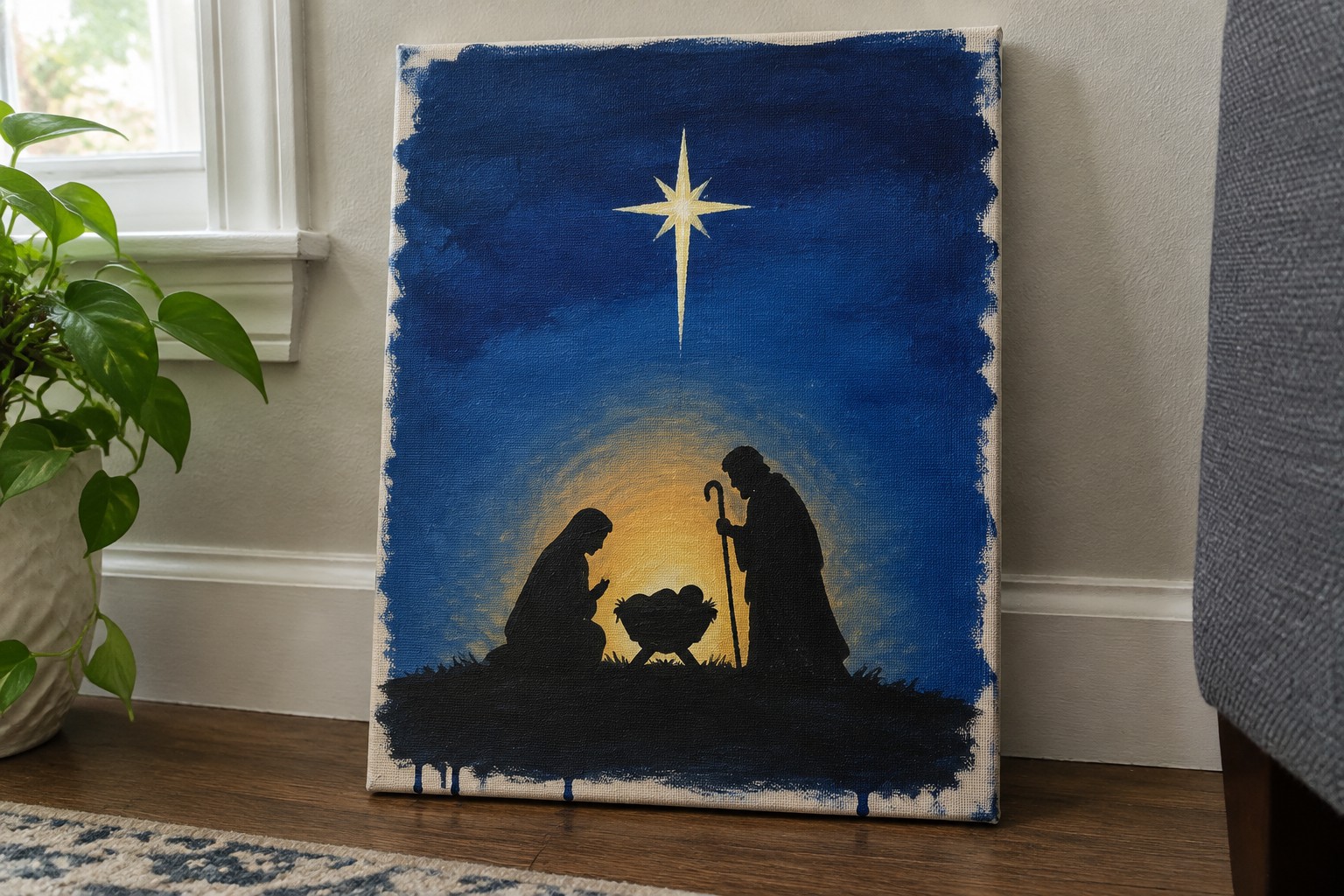 Acrylic painting of nativity silhouettes under glowing star with yellow light on blue canvas