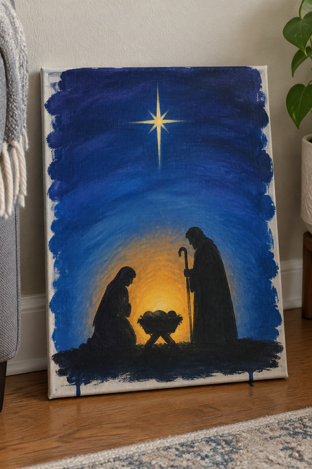 Acrylic painting of nativity silhouettes under glowing star with yellow light on blue canvas