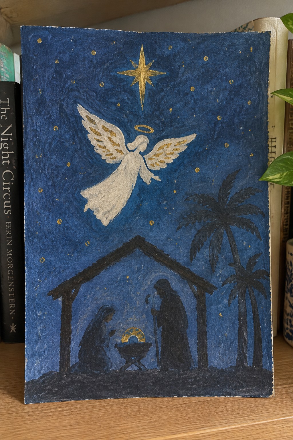 Nativity scene with golden star, white angel, and holy family in stable by palm trees