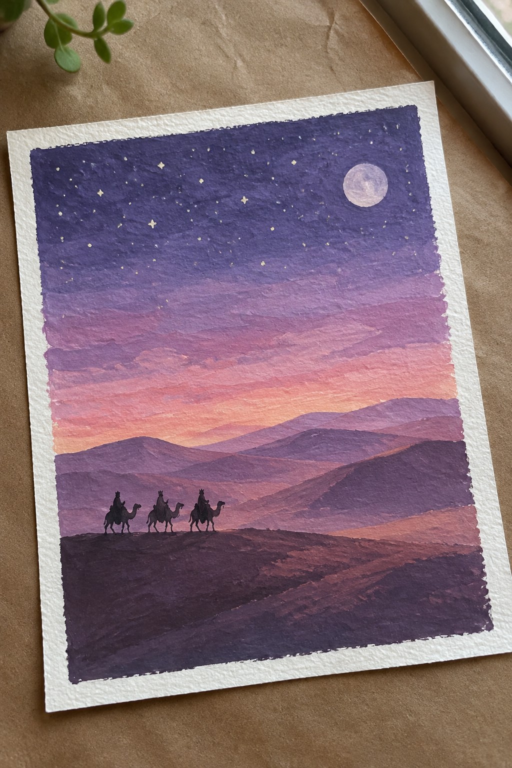 Watercolor of three camel riders silhouetted against purple mountains under moon and starry sky.
