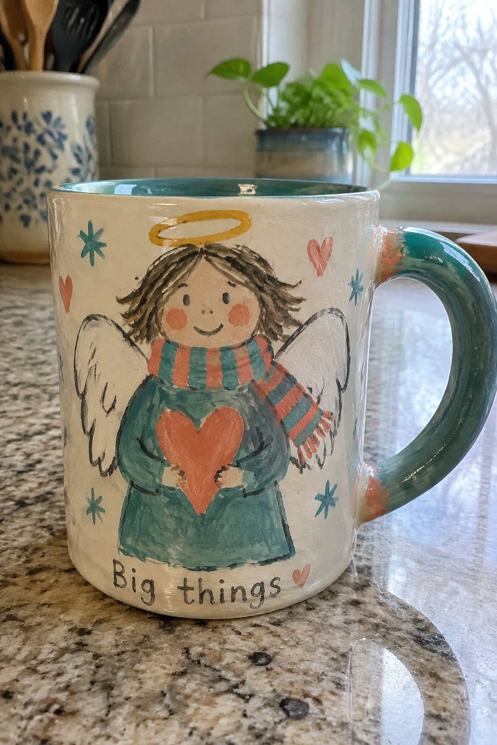 Hand-painted ceramic mug with angel in teal dress holding heart and 