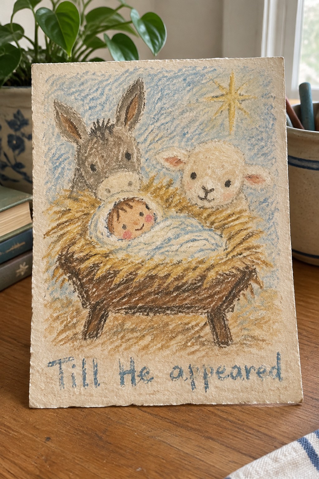Pastel nativity drawing of baby in manger with donkey, lamb, yellow star, and blue text.
