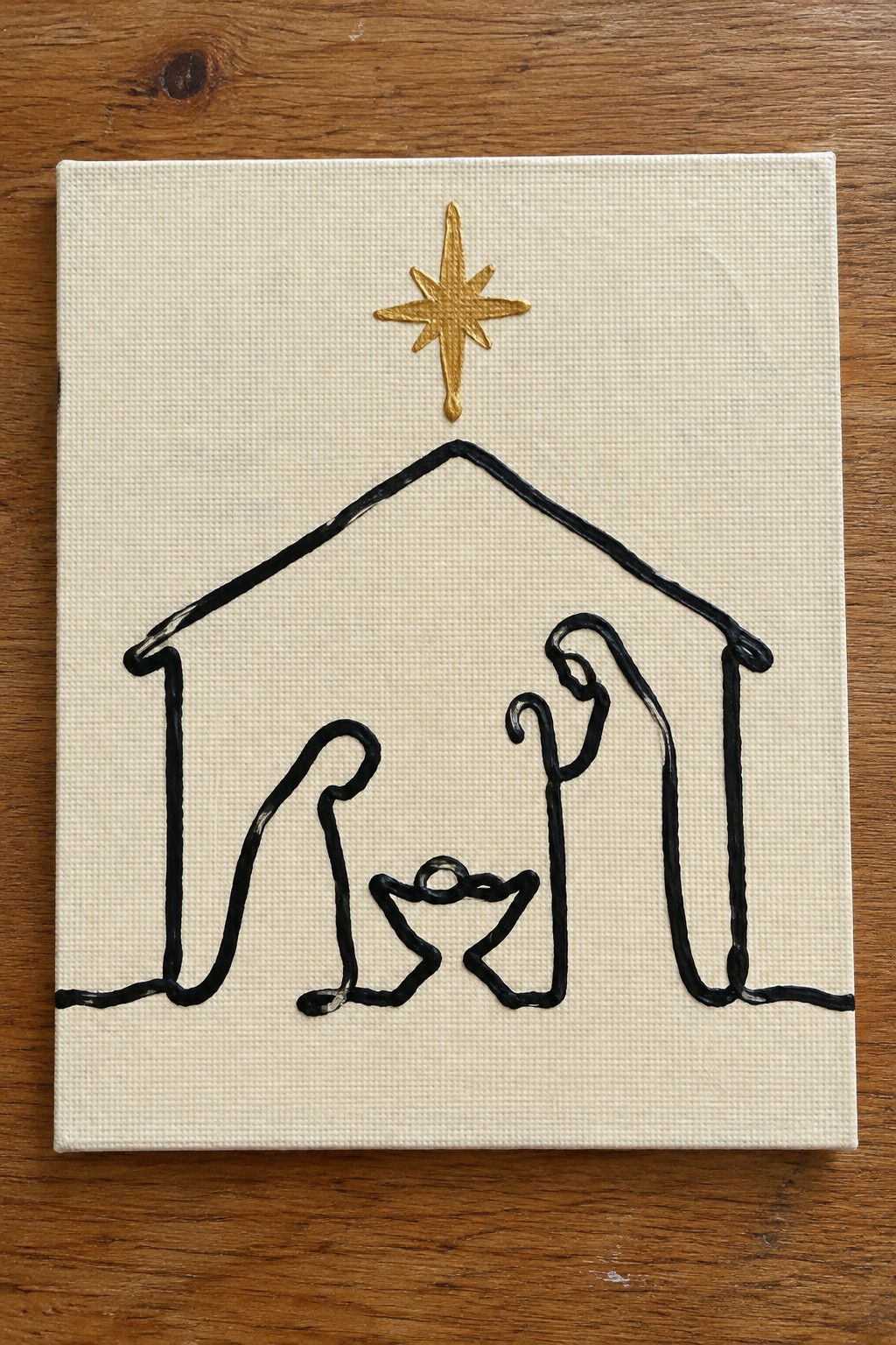 Minimalist black line art of nativity scene with gold star on white canvas
