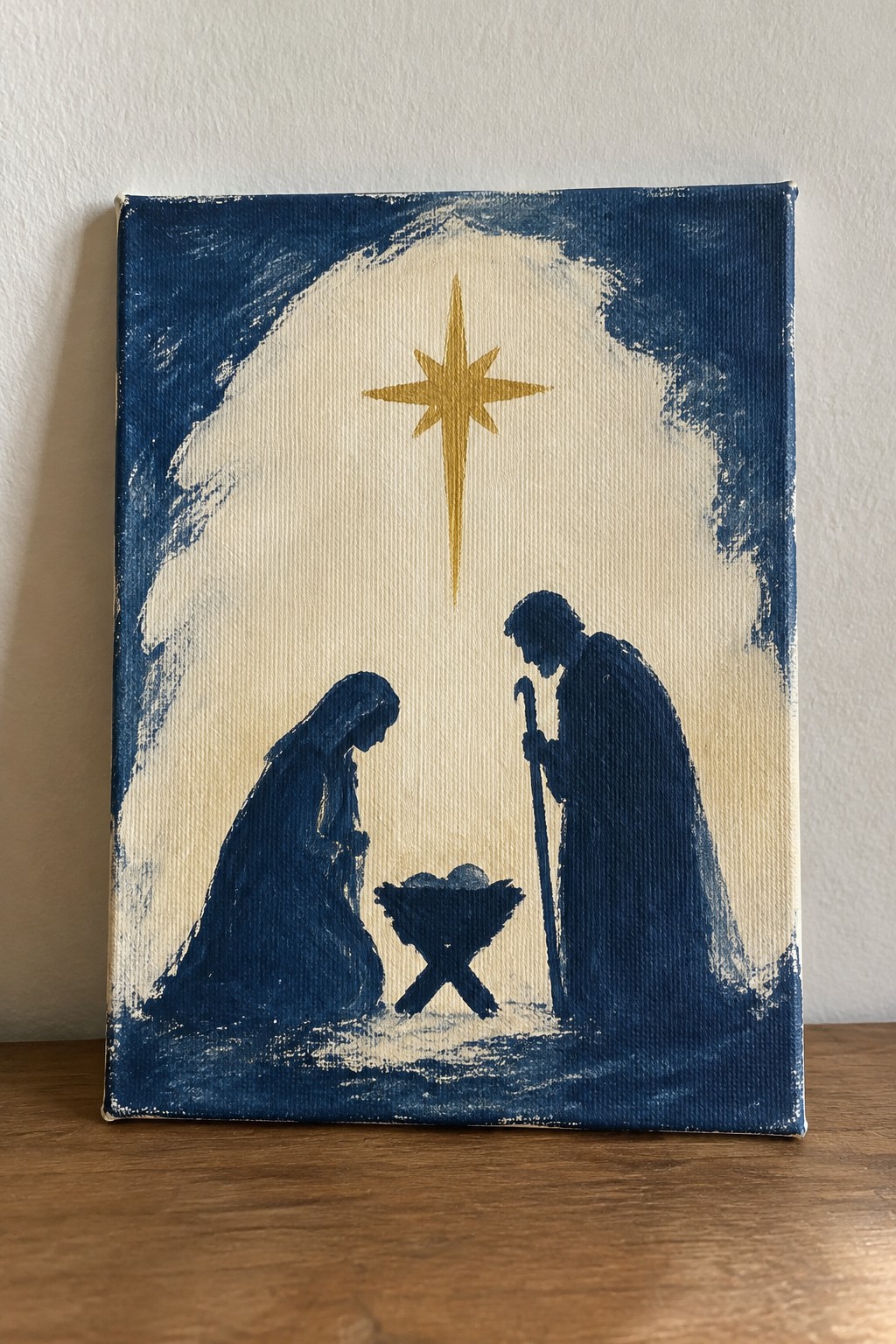 Blue-painted nativity scene with robed figures, manger, and golden star above