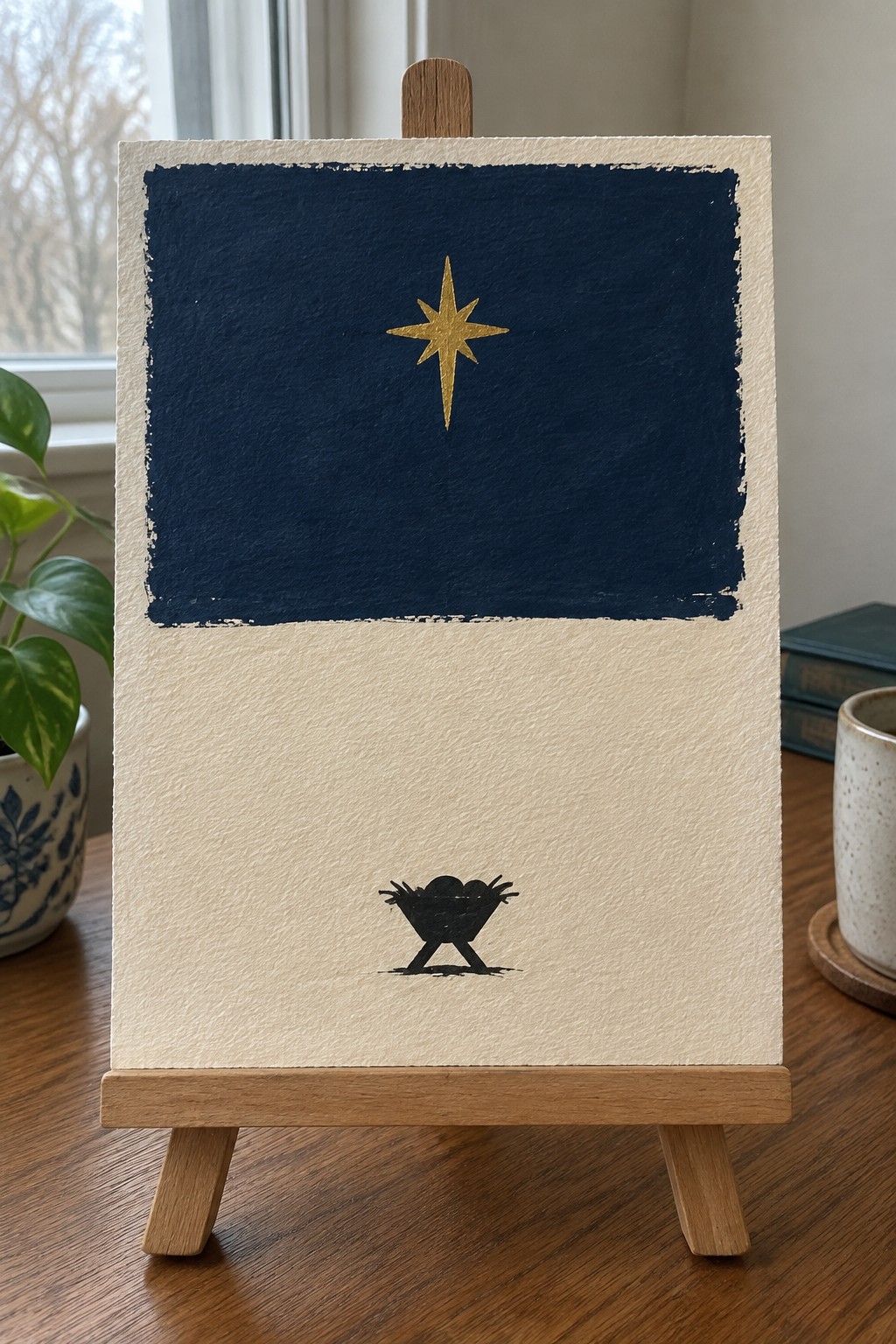 Mini canvas on easel with navy blue top, gold star, and cream bottom with black manger silhouette