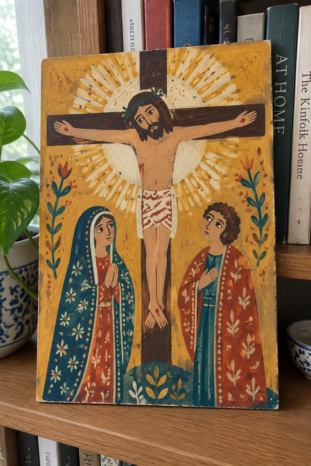 Colorful folk art of Jesus crucified with two robed mourners praying on yellow sunburst background
