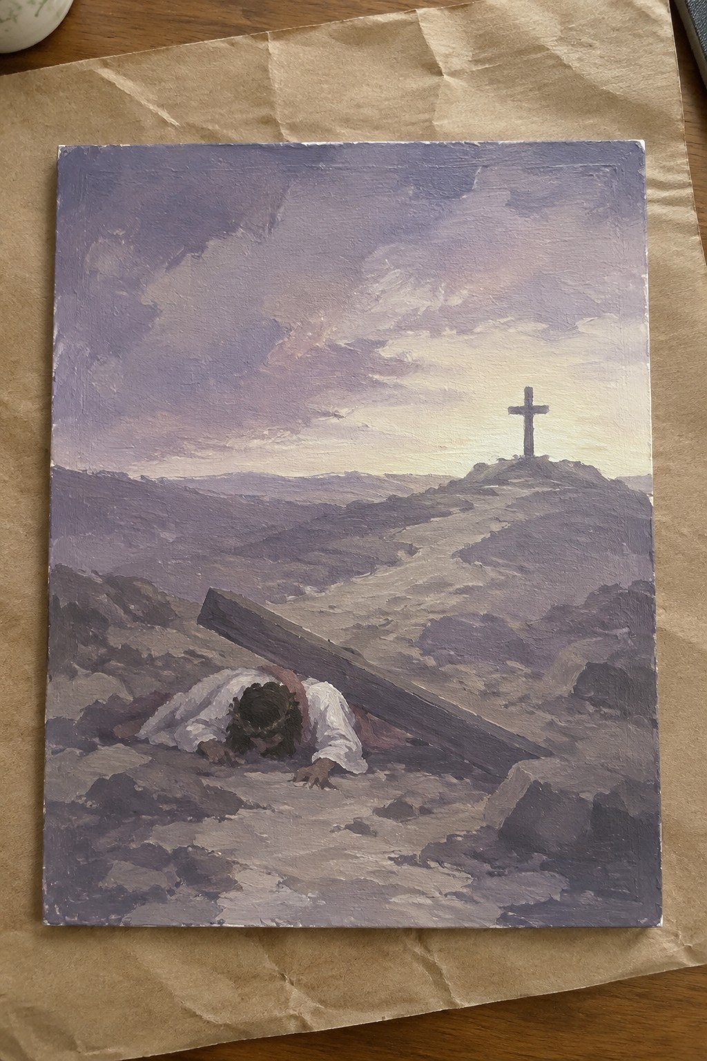 Jesus fallen carrying wooden cross on rocky path toward hilltop crucifix under purple sky