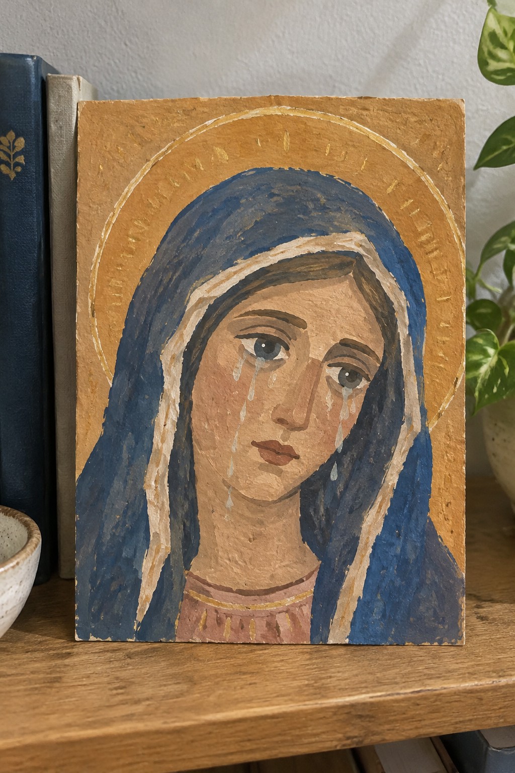 Hand-painted icon of weeping woman in blue veil with golden halo on wood