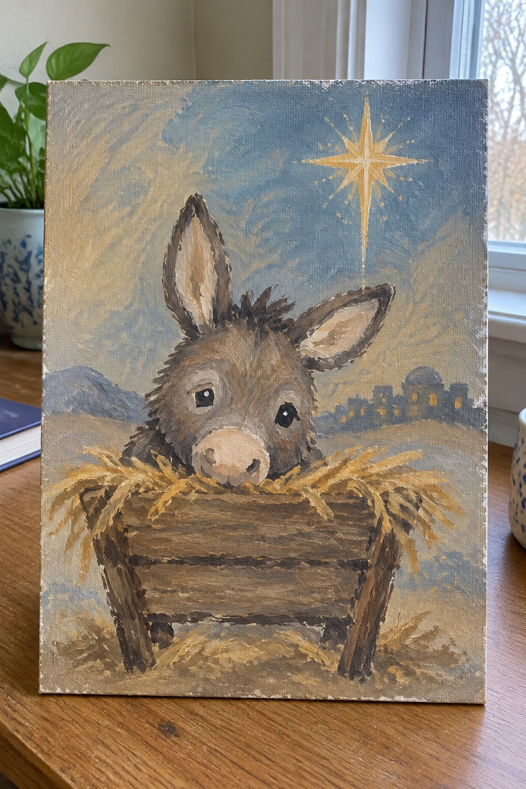 Brown donkey peeking from straw-filled wooden manger beneath glowing yellow star at night