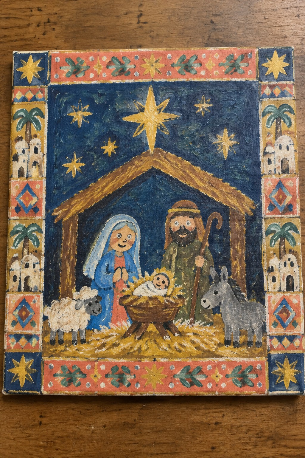 Folk art nativity scene with Mary in blue, Joseph, baby Jesus, sheep, donkey and bright star.