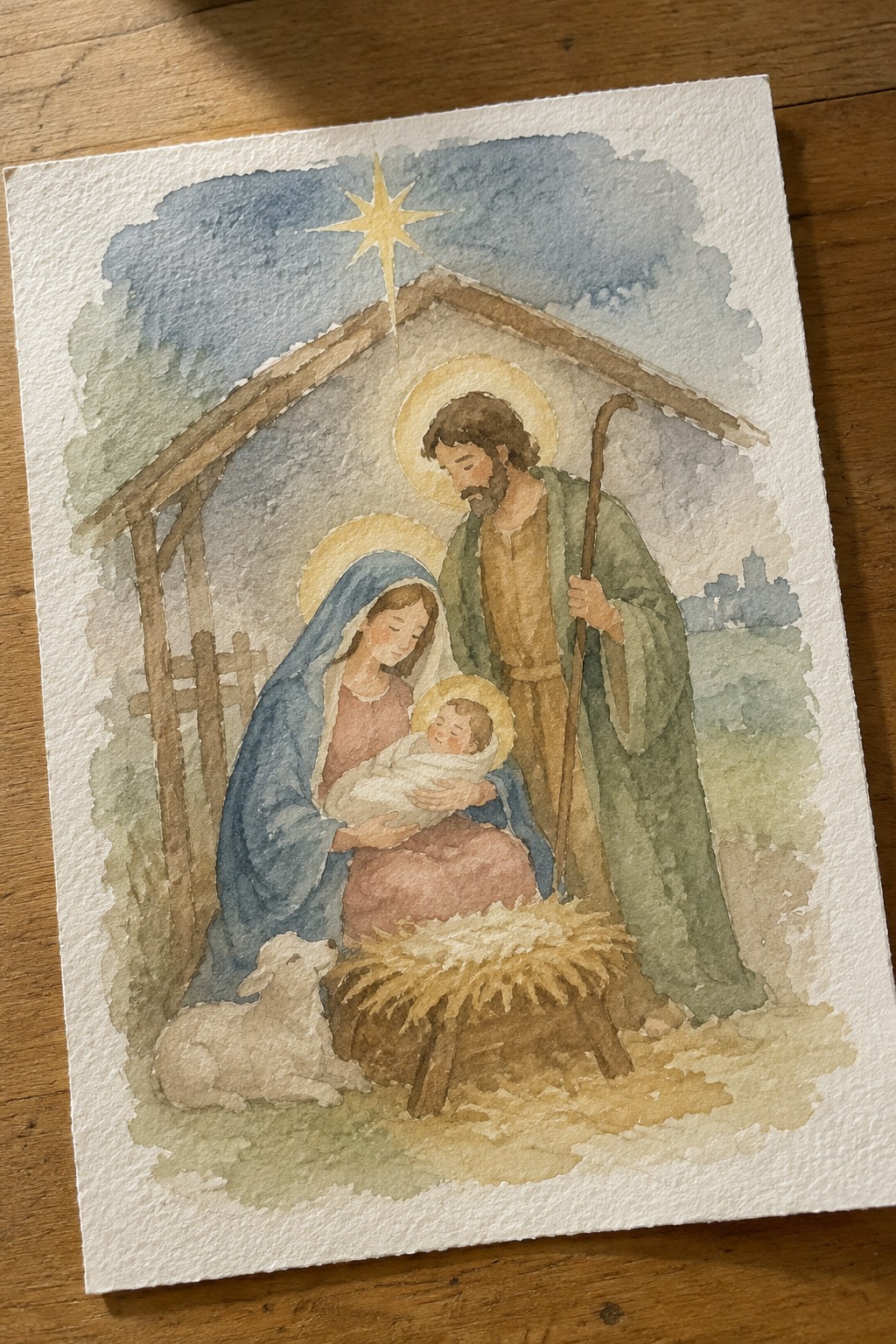 Watercolor nativity: Mary in blue veil, Joseph with staff, haloed baby in manger under golden star