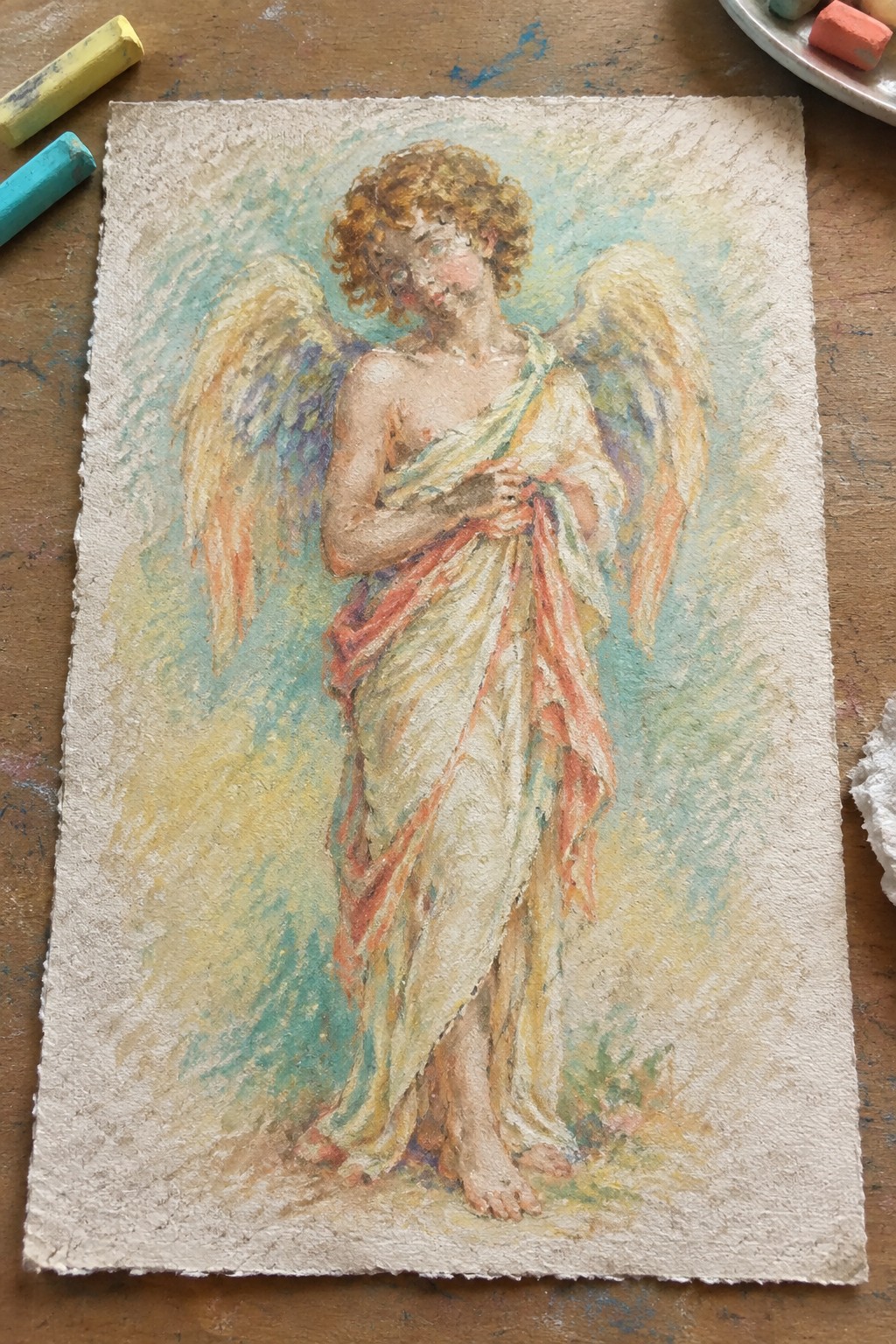 Pastel drawing of a curly-haired angel with golden wings in flowing white-red robes