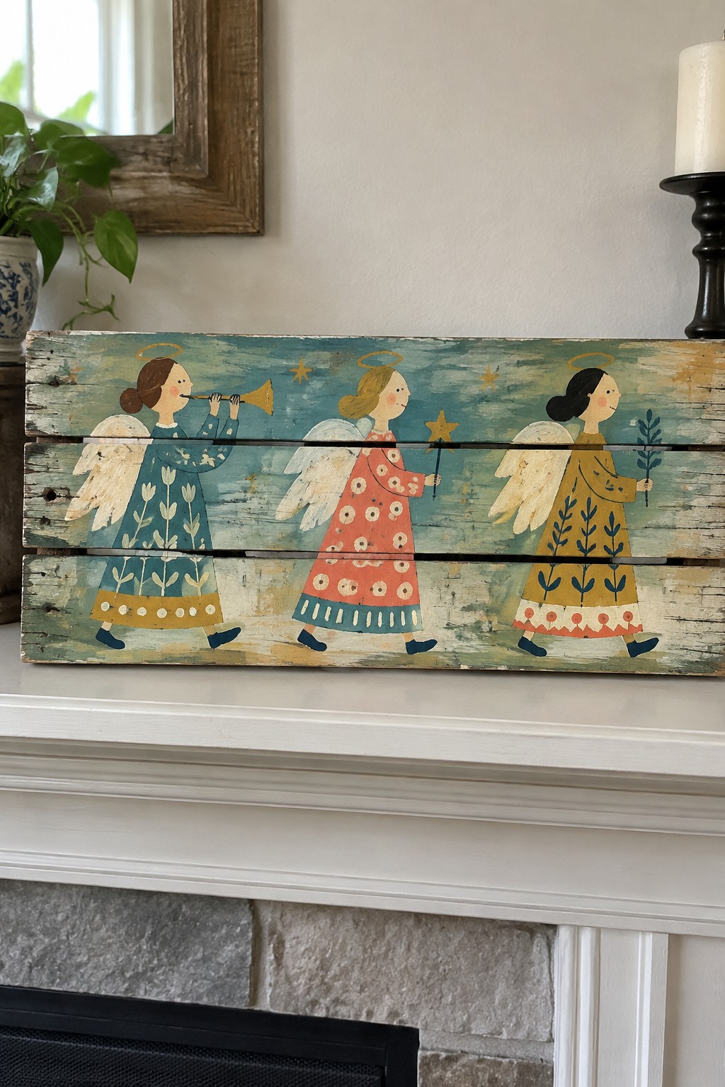 Three folk-art angels in blue, red, and yellow dresses on rustic wooden plank mantel