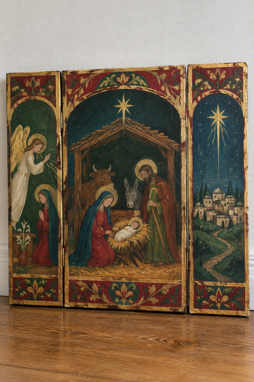 Gold-framed triptych with angel in white, Mary in red-blue, Joseph, manger, ox, donkey, and Bethlehem star.