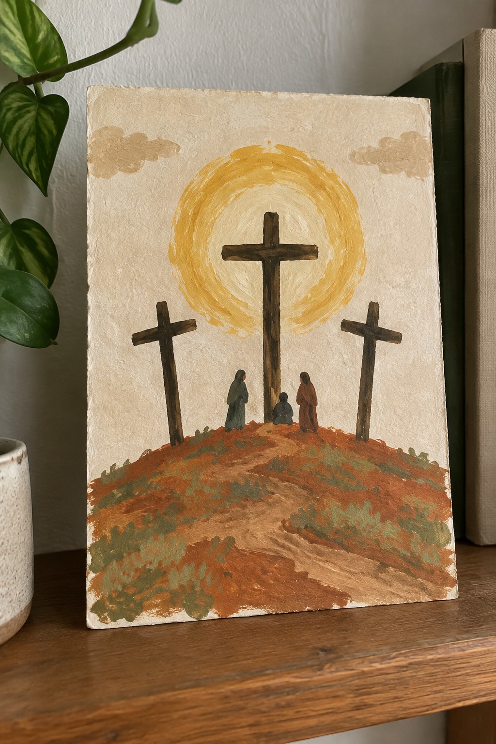 Three wooden crosses on reddish hill with robed figures beneath golden sun