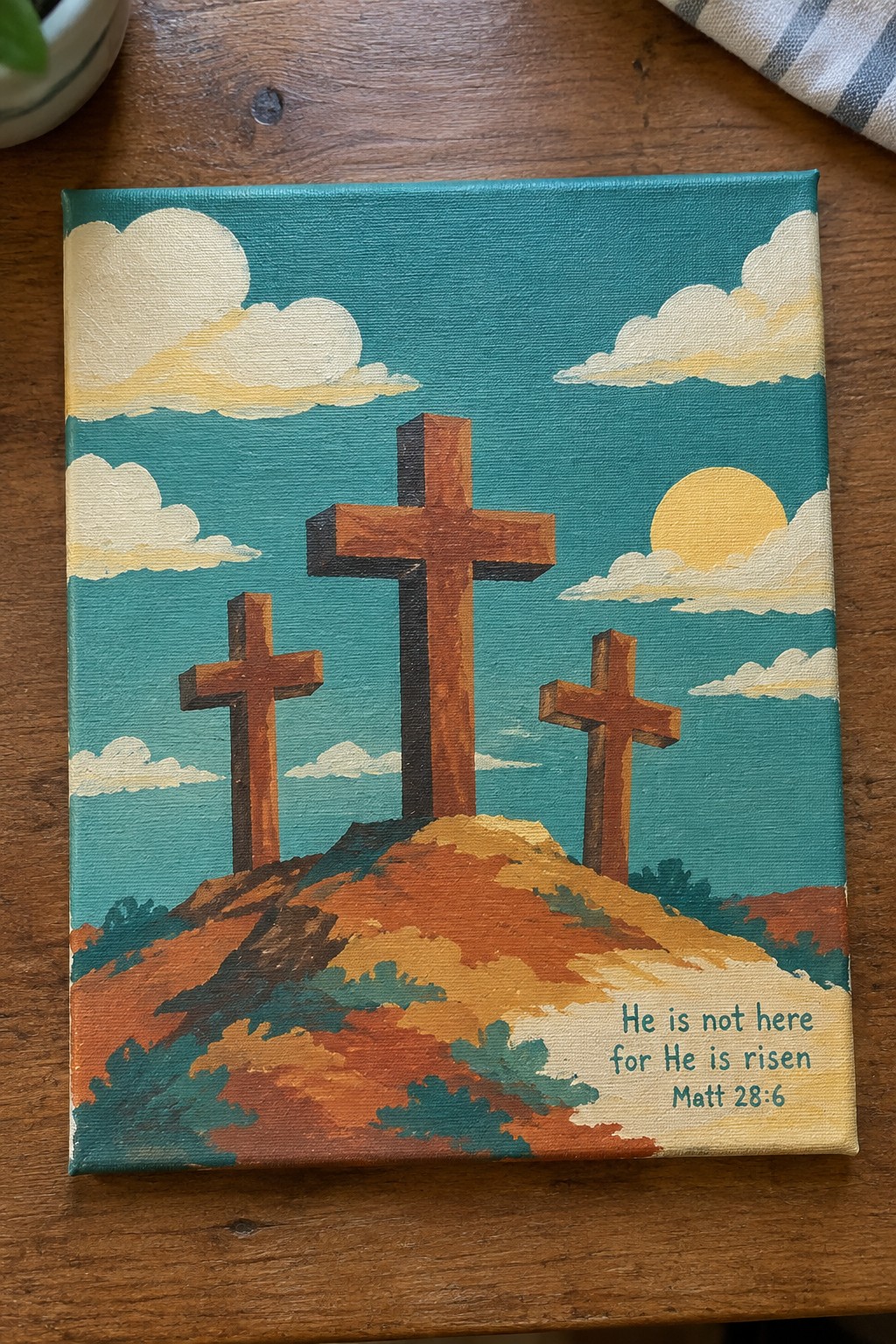 Three crosses on a hill under teal sky with sun, clouds, and risen verse text.