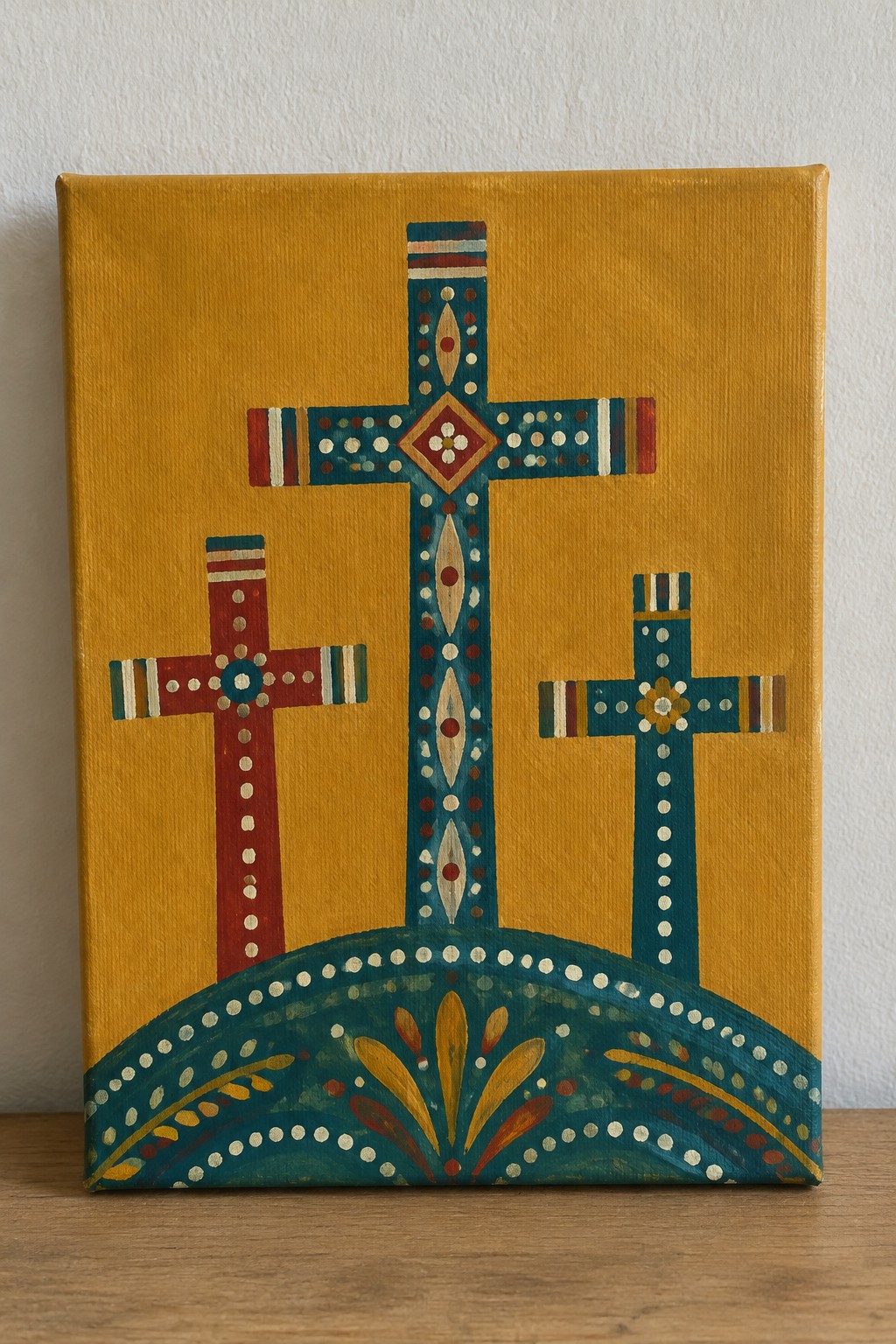 Three ornate crosses on yellow canvas above decorative teal arch with patterns