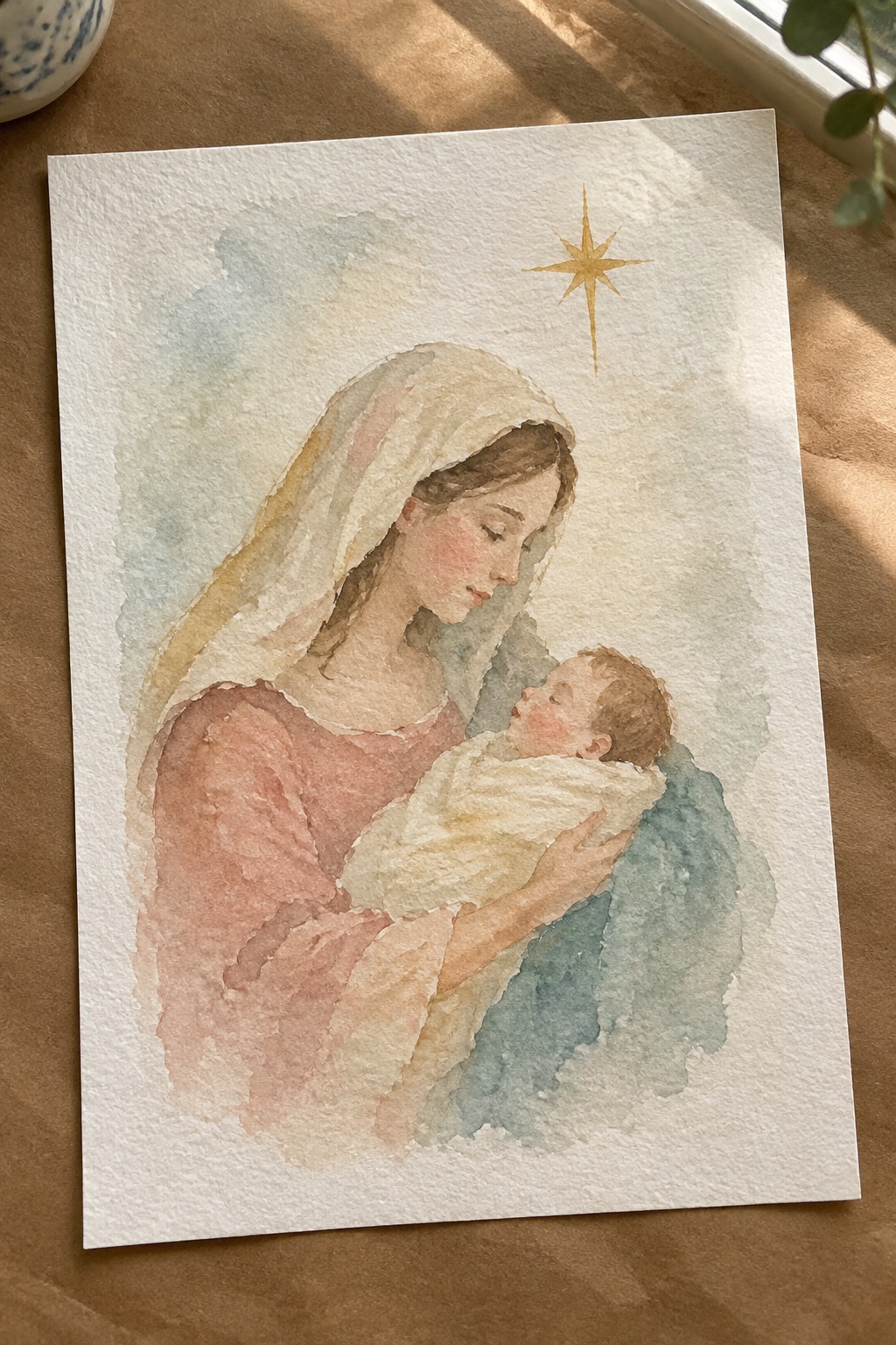 Watercolor of veiled woman in pink holding swaddled baby beneath golden star