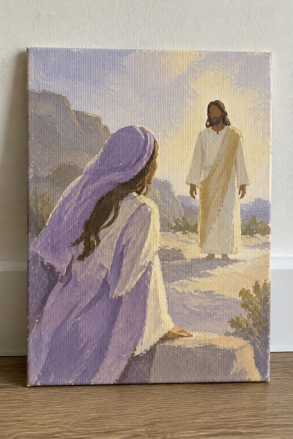 Painting of a woman in purple robes kneeling before Jesus on a rocky path
