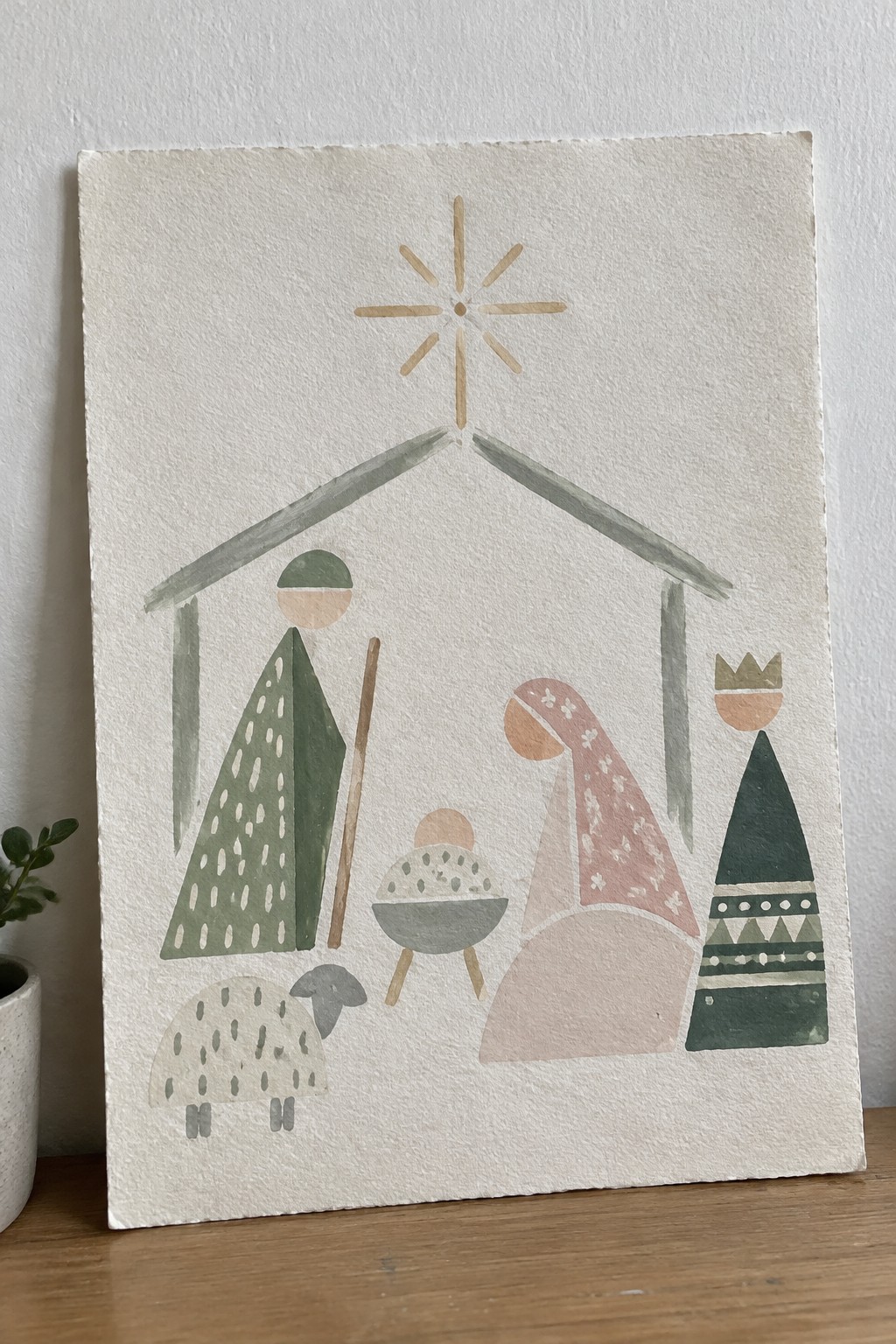 Abstract watercolor nativity with robed figures, crowned king, sheep, manger, and shining star.