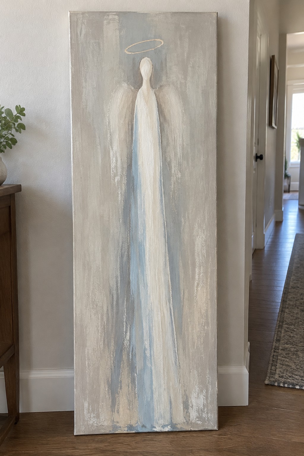 Tall abstract angel painting with halo and wings in neutral hallway setting.