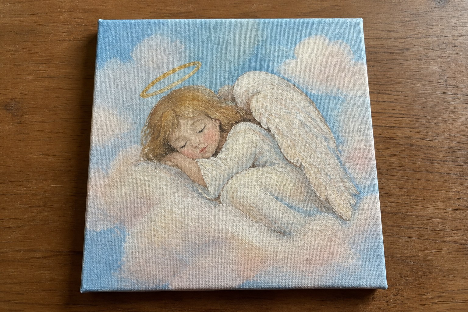 Blonde angel in white gown sleeps on clouds with golden halo and white wings.
