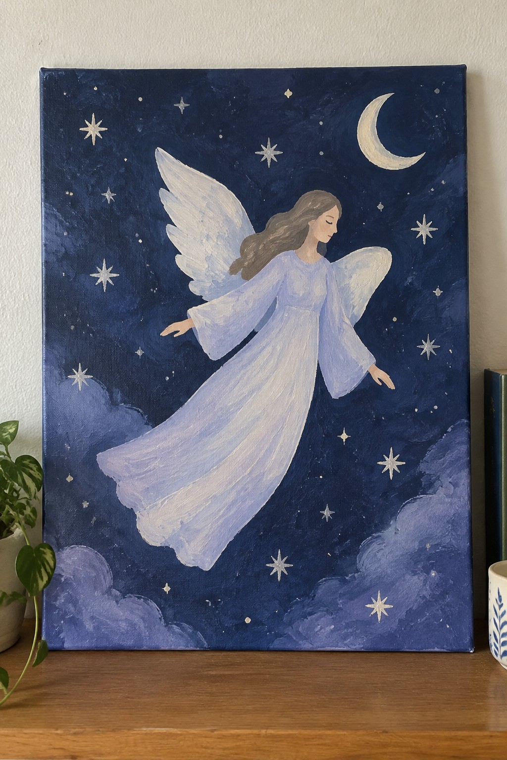 Angel in flowing blue dress with white wings flying in dark starry sky with moon.