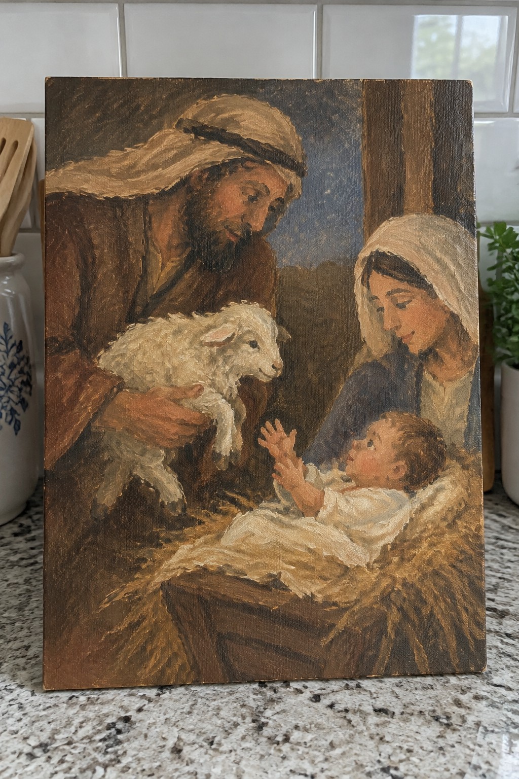Bearded man in brown robe holds white lamb near woman and baby in manger