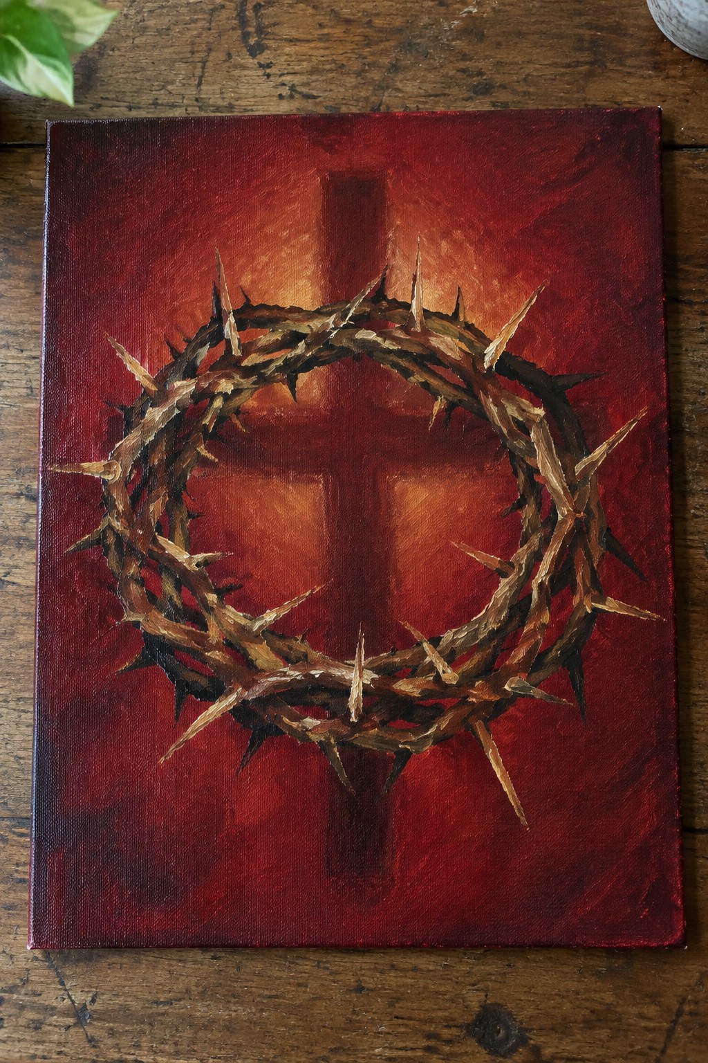 Crown of thorns painting over cross on textured red-orange canvas on wood