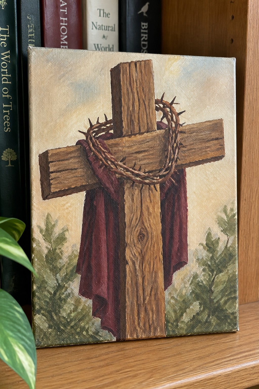 Wooden cross with crown of thorns and red cloth on canvas before books