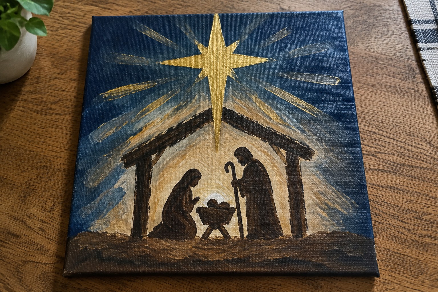 Nativity painting with Mary kneeling, Joseph by manger under golden star with light rays